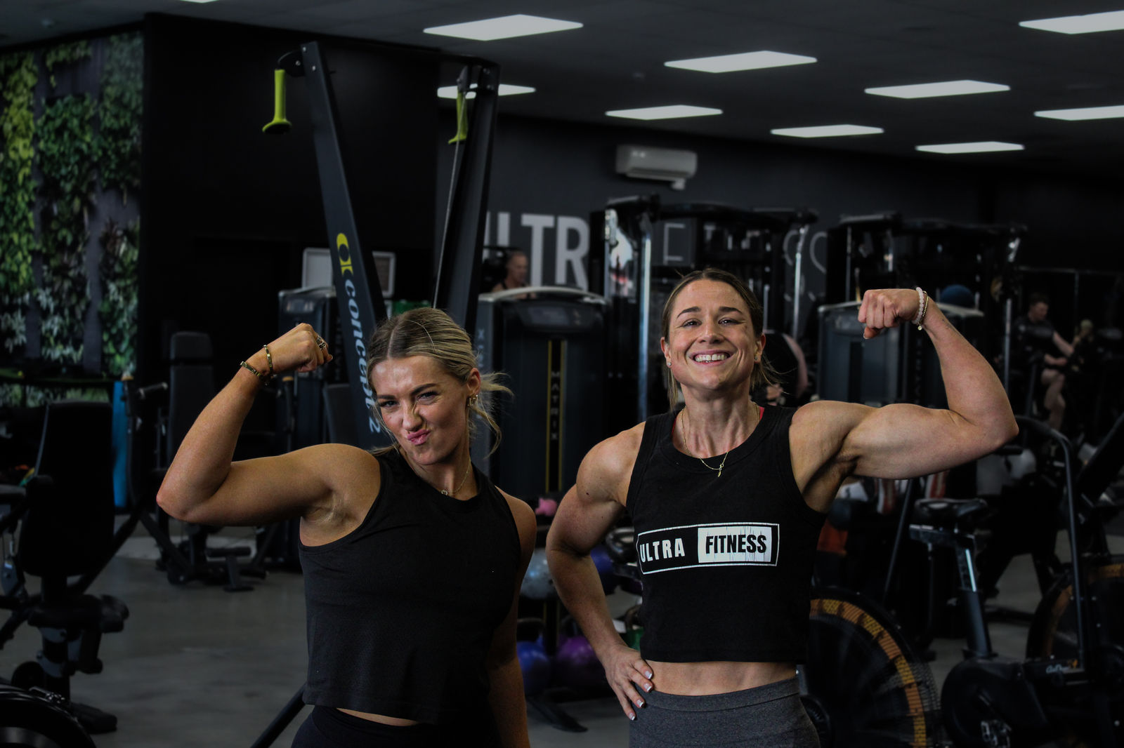 Two members flexing and laughing on the gym floor
