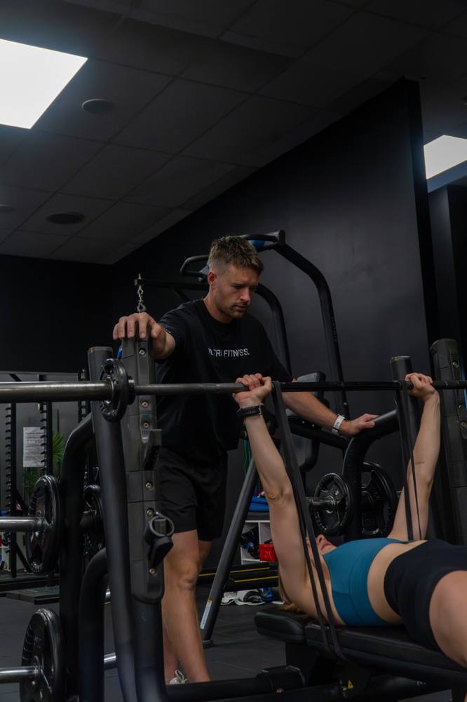 Coach spotting an athlete on the bench press